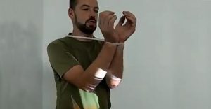 Muž ukazuje, ako jednoduchým spôsobom vymaniť svoje ruky zo zovretia eska pásky